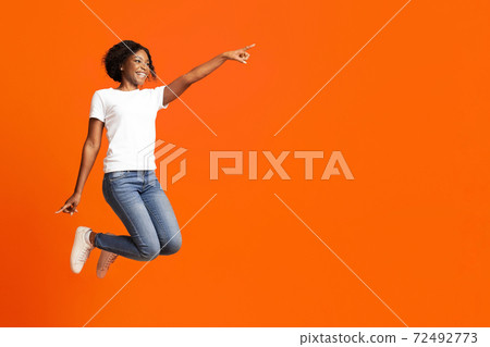 Excited black woman jumping up and showing copy space Excited black woman jumping up and showing copy space 72492773