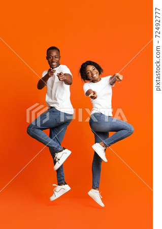 Emotional black couple posing on orange studio background Emotional black couple posing on orange studio background 72492777
