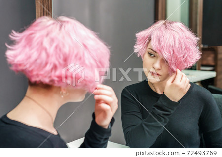 Girl looking in the mirror at her new hairstyle Girl looking in the mirror at her new hairstyle 72493769