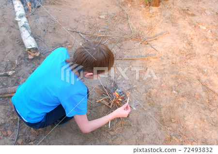 Child boy making bonfire from firewoods branches nature sitting near it. Child boy making bonfire from firewoods branches nature sitting near it. 72493832