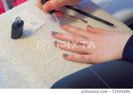 Woman covering nails applying top coat on gel polish at home, hands closeup. Woman covering nails applying top coat on gel polish at home, hands closeup. 72493890