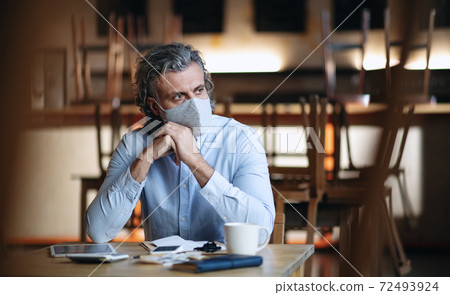 Frustrated owner sitting at table in closed cafe, small business lockdown due to coronavirus. 72493924