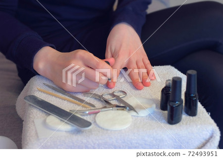 Woman is applying primer on nails before cover it shellac gel polish, closeup. Woman is applying primer on nails before cover it shellac gel polish, closeup. 72493951