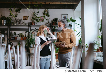 Man and woman managers in closed cafe, small business lockdown due to coronavirus. Man and woman managers in closed cafe, small business lockdown due to coronavirus. 72493986