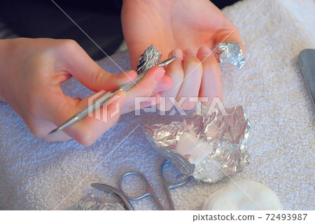Woman is removing gel polish shellac from nails using pusher, manicure at home. Woman is removing gel polish shellac from nails using pusher, manicure at home. 72493987