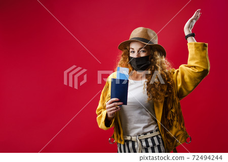 Young woman in a studio holding plane tickets, coronavirus and travelling concept. 72494244
