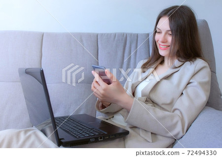 Woman working typing on laptop and reading message on smartphone, distant work. Woman working typing on laptop and reading message on smartphone, distant work. 72494330