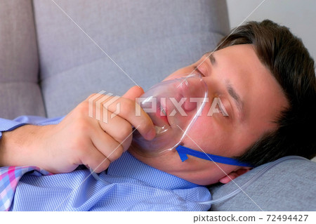 Sick man in oxygen mask due to difficulty in breathing in coronavirus pandemic. Sick man in oxygen mask due to difficulty in breathing in coronavirus pandemic. 72494427