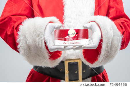 Close up hands of Santa Claus holding device with postcard decoration on the screen 72494566