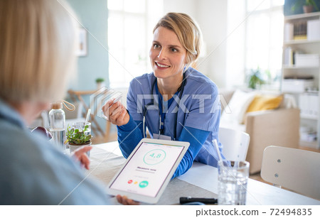 Caregiver or healthcare worker with senior woman patient, measuring blood glucose indoors. 72494835