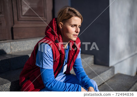 Woman caregiver, nurse or healthcare worker sitting outdoors on the way to work. 72494836