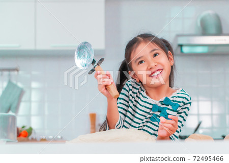 Happy Asian girl having fun preparing pizza dough in kitchen and smile for funny child activity concept. Happy Asian girl having fun preparing pizza dough in kitchen and smile for funny child activity concept. 72495466