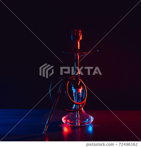 glass hookah with a metal bowl with hot coals on a black background on a table 72496162