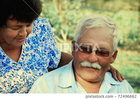 Loving mature cople hugs on a summer day in the park.Senior couple are sitting outdoors.An elderly 72496662