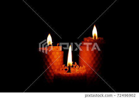 Close-up of three small yellow candles on a black background. Close-up of three small yellow candles on a black background. 72496902