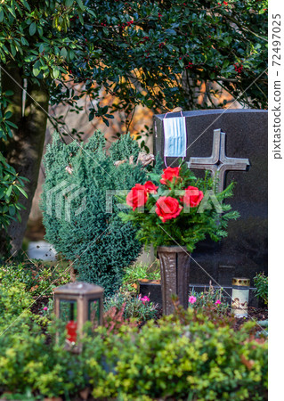 Facemask lying on grave of family members with a facemask during the pandemic 72497025