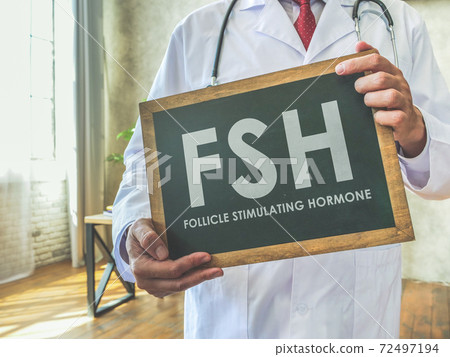 Doctor holds sign FSH Follicle stimulating hormone on the desk. Doctor holds sign FSH Follicle stimulating hormone on the desk. 72497194