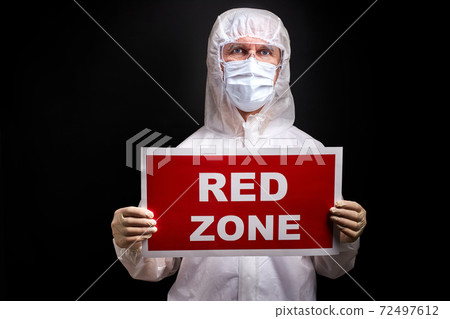 portrait of doctor male in protective medical suit holding tablet with RED ZONE inscription 72497612