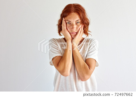 sad redhead woman touching her face, she is upset 72497662