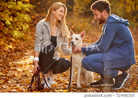positive caucasian couple enjoy spending time with dog in the forest, at countryside 72498103