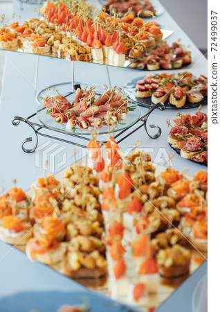 Sandwiches, canapes and cakes on the festive table. A wide variety of snacks Sandwiches, canapes and cakes on the festive table. A wide variety of snacks 72499037