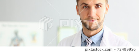 Handsome young doctor standing in modern clinic Handsome young doctor standing in modern clinic 72499956