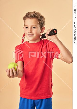Adorable sporty boy holding tennis racket and ball 72500139