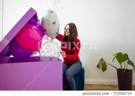 The brunette girl with big birthday present and balloons The brunette girl with big birthday present and balloons 72500714