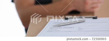 Male courier waiting for client sign while delivering parcel 72500903