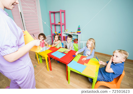 The teacher tells the children how to make a postcard 72501623