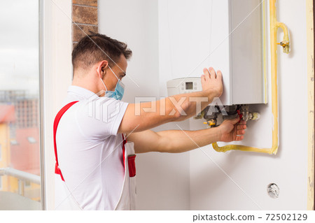 The plumber in a medical mask works during a pandemic 72502129