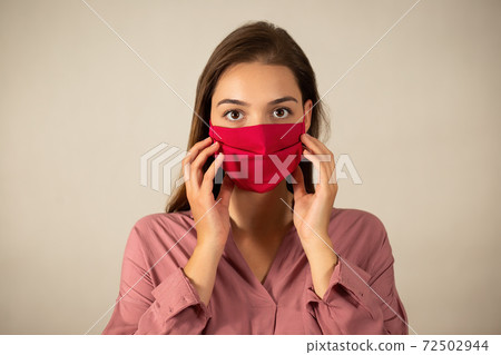 Young woman touching red mask on the face in studio Young woman touching red mask on the face in studio 72502944