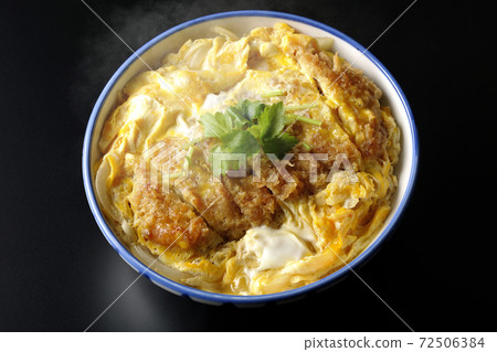 A single shot of a hot katsudon in a bowl with a black background (overhead view) 72506384