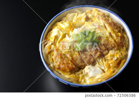 A single shot of a hot katsudon in a bowl with a black background (overhead view) 72506386