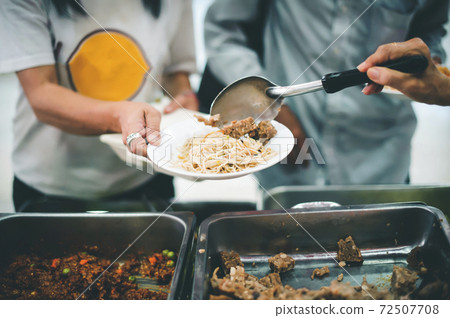 Volunteers give food to the poor Volunteers give food to the poor 72507708