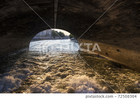 A pleasure boat sails under a bridge over the Seine in Paris 72508304