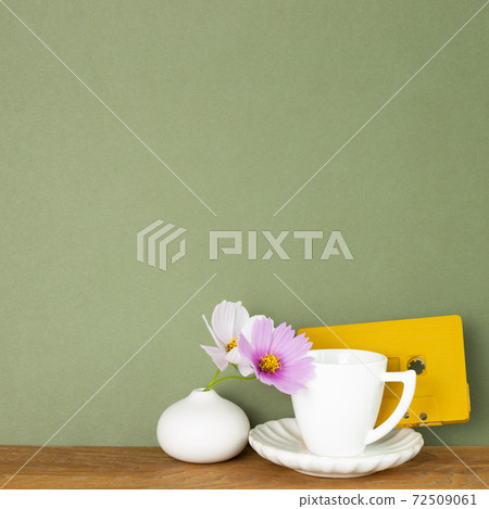Coffee cup with common cosmos flowers and audio cassette tape on wooden table. Khaki green background Coffee cup with common cosmos flowers and audio cassette tape on wooden table. Khaki green background 72509061