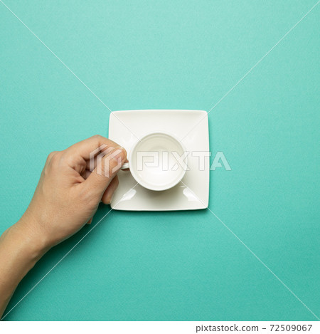 Female hand holding white empty mug cup on mint green background. top view 72509067