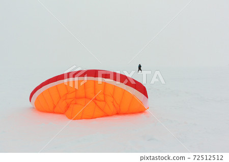 Man training with a kite on frozen river Man training with a kite on frozen river 72512512