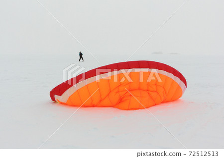Man training with a kite  on  frozen river 72512513
