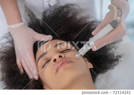 Young woman during cosmetic hardware procedure 72514281