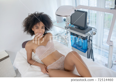 Joyful young woman reclining on daybed Joyful young woman reclining on daybed 72514460