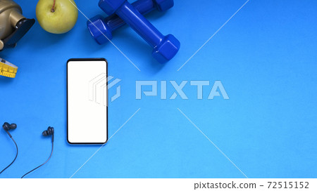 The top view of a blank screen smartphone is putting on a blue exercise mat by gym stuff. The top view of a blank screen smartphone is putting on a blue exercise mat by gym stuff. 72515152