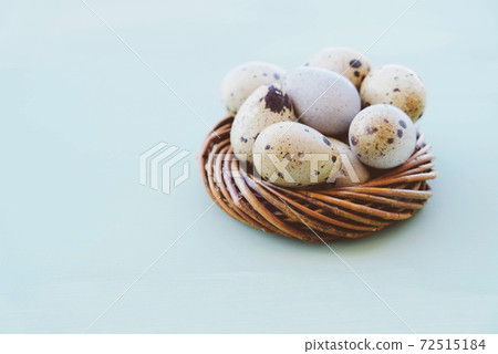 Quail eggs in bird nest on light blue background, close up. Quail eggs in bird nest on light blue background, close up. 72515184
