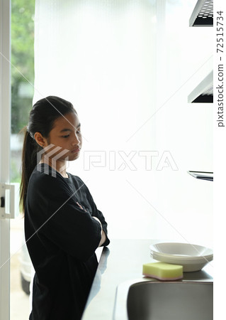 Portrait of a young Asian girl feeling unhappy to washing dishes in the kitchen at home. Portrait of a young Asian girl feeling unhappy to washing dishes in the kitchen at home. 72515734