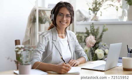 Motivated millennial female remote worker doing paperwork using laptop headphones 72515952