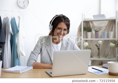 Capable female designer working from home by laptop in headphones Capable female designer working from home by laptop in headphones 72515956