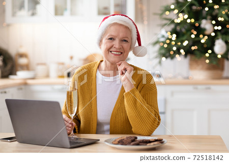 Elegant old woman in Santa hat using 