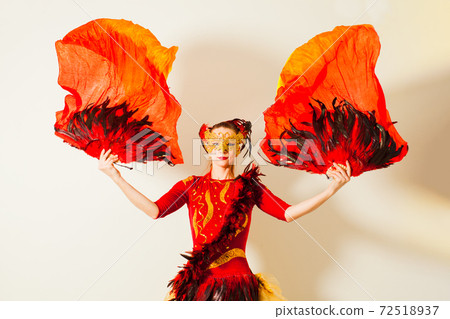 Woman in bright costume acting like misterious fire bird 72518937
