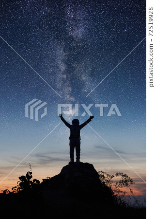Astronaut standing on top of mountain under night sky. Astronaut standing on top of mountain under night sky. 72519928